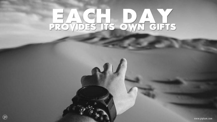 Each-day-provides-its-own-gifts-inspirational-quote-mans-hand-desert-sand